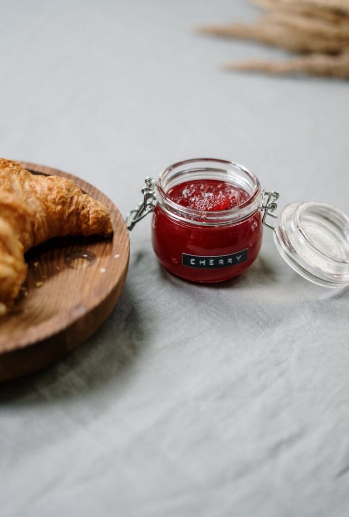 A delicious croissant served with cherry jam, perfect for a breakfast spread.