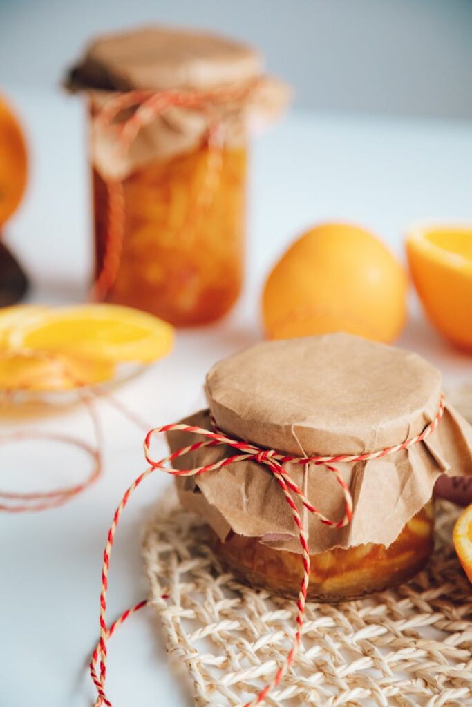 Homemade orange jam in rustic jars with fresh oranges, captured in a bright and inviting scene.