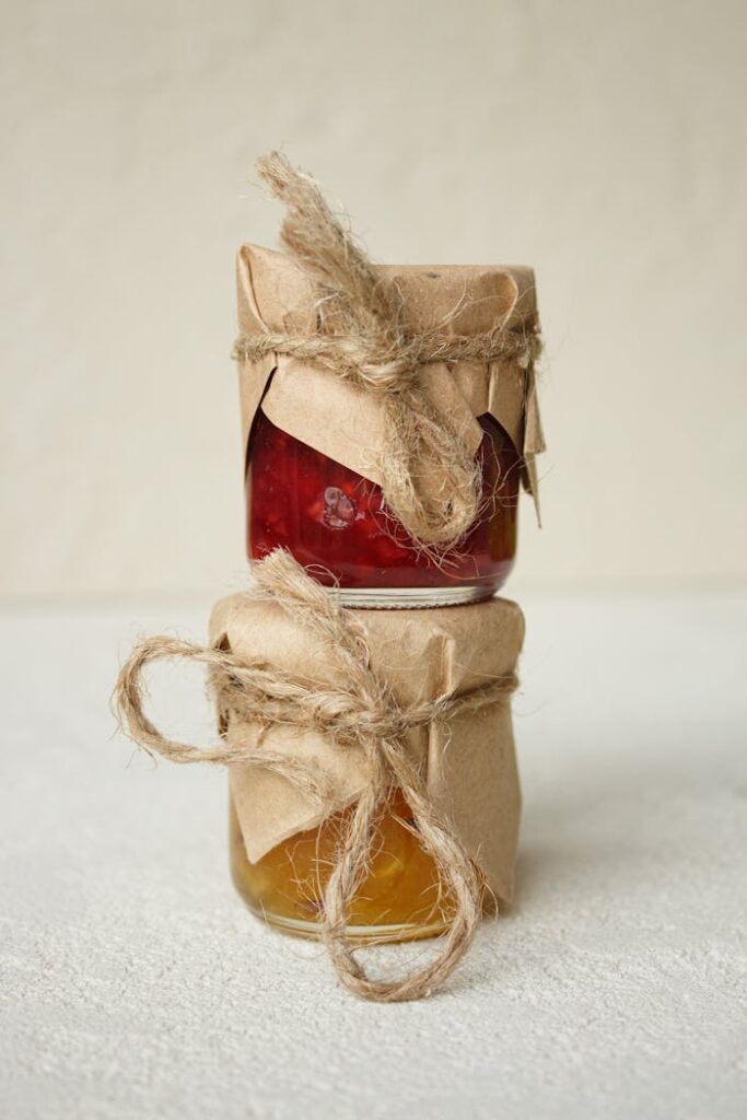 Close-up of stacked jars of homemade jams wrapped in rustic paper and twine.